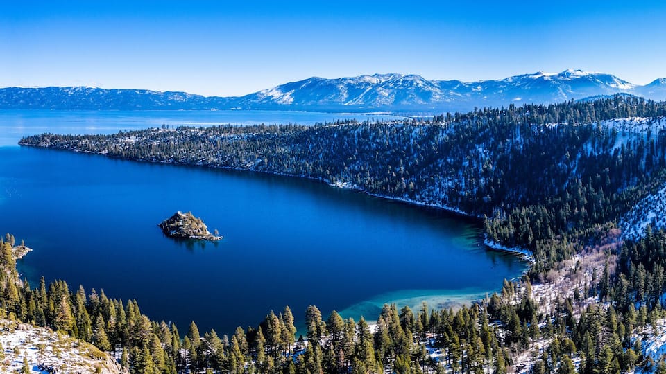 A snow-covered mountain landscape with a lake and a small island.