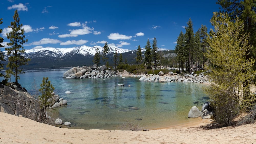 Un lac aux eaux limpides, entouré de montagnes et d’arbres.