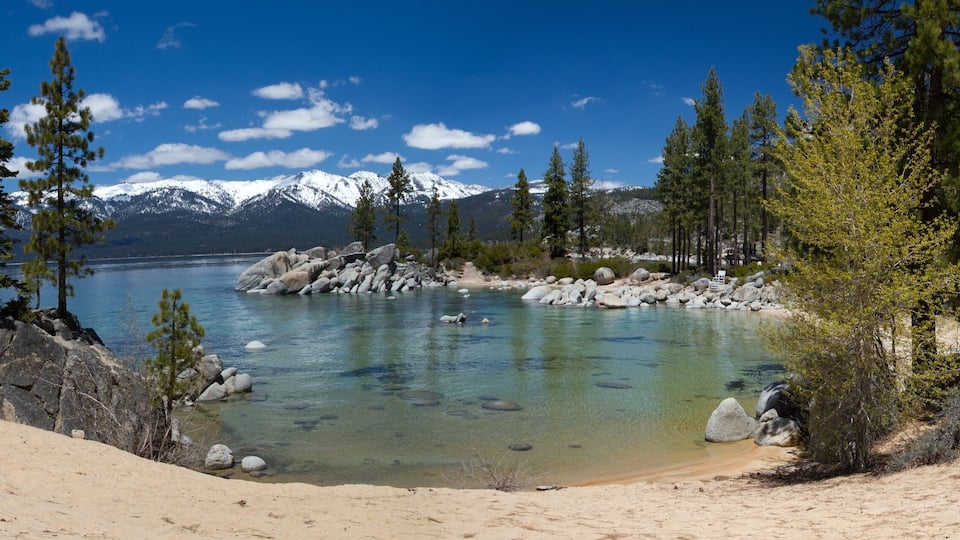 A clear lake surrounded by mountains and trees.