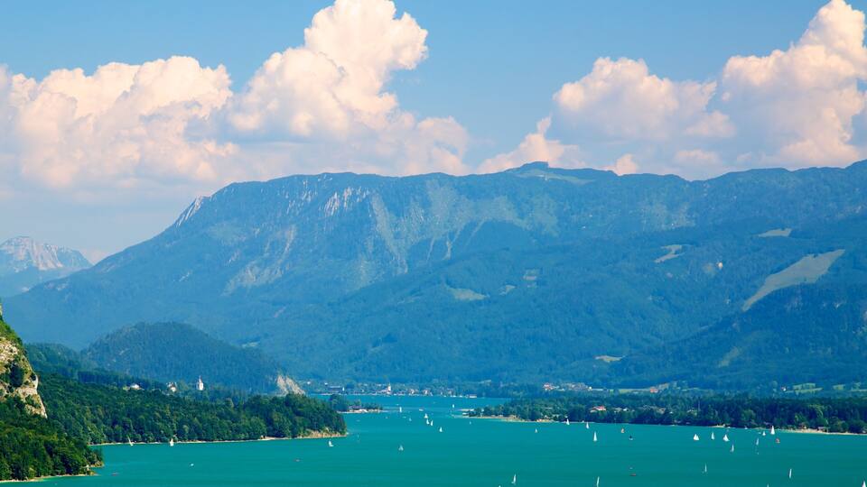 A lake surrounded by mountains with sailboats on the water.