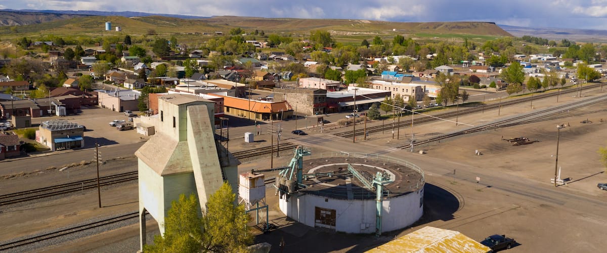 A town with a train station, railway tracks, and a mountainous backdrop.