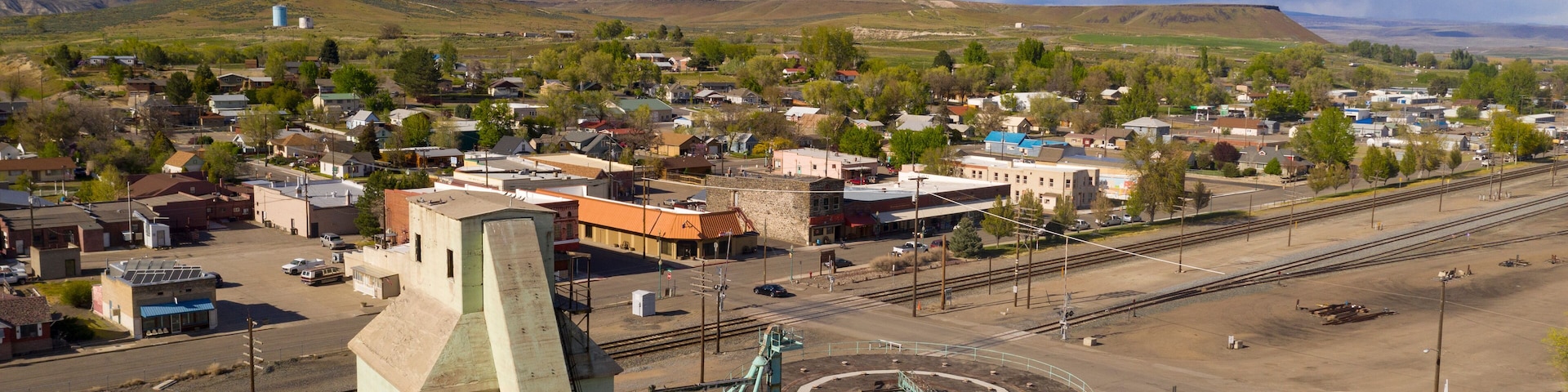 A town with a train station, railway tracks, and a mountainous backdrop.