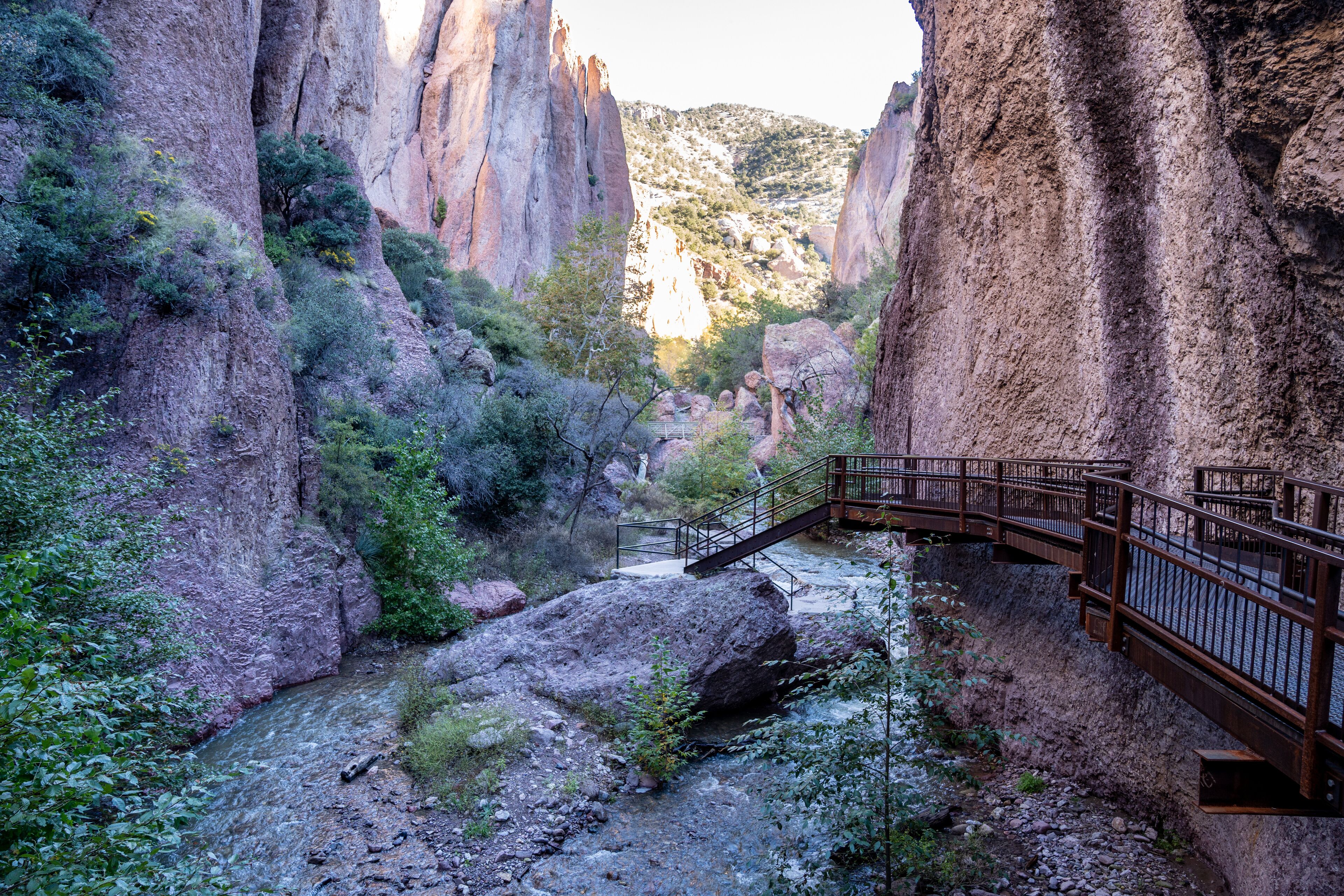 A canyon with a wooden bridge and a river.