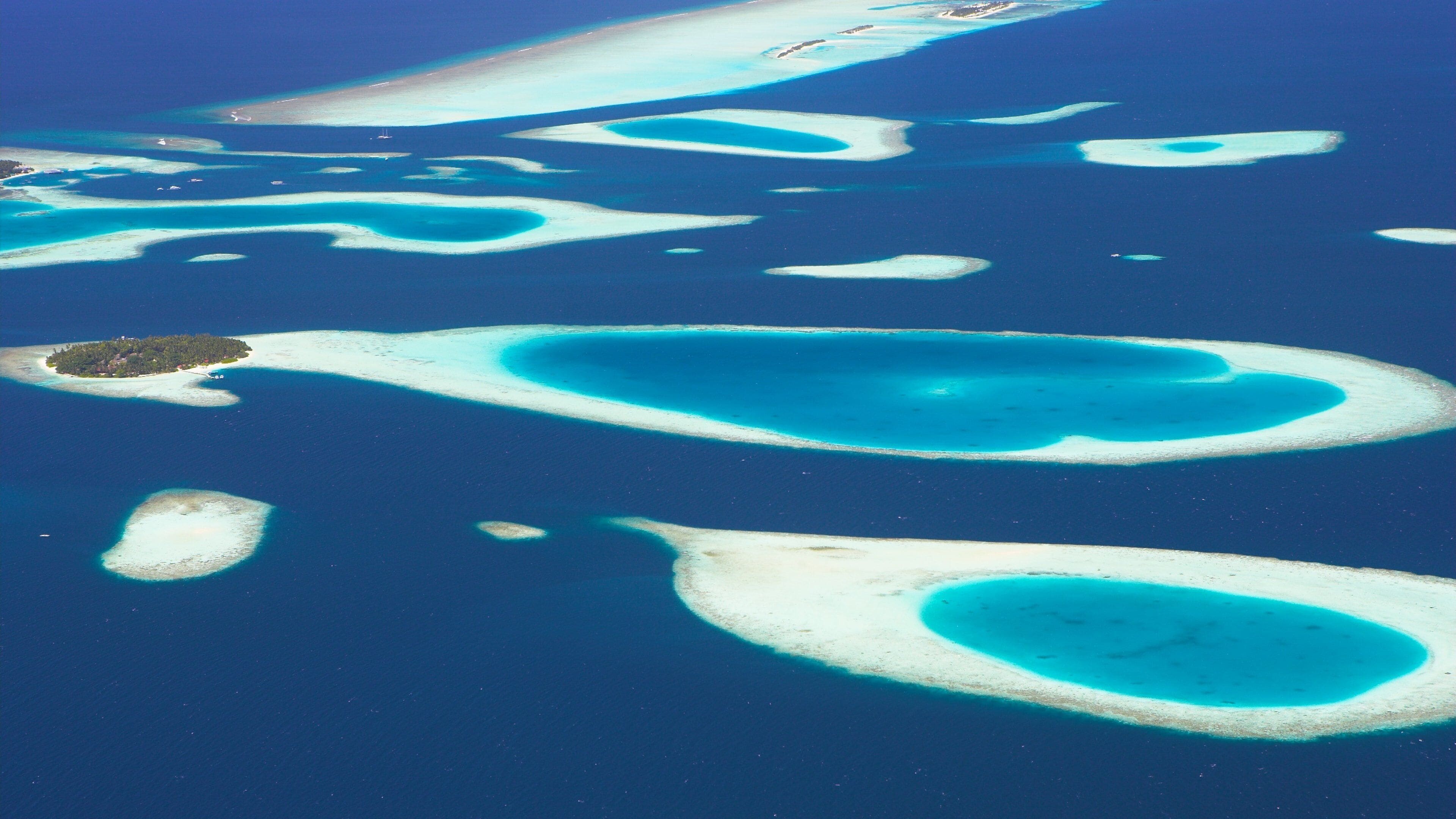 Um conjunto de atóis turquesa com praias de areia branca e águas azul-claras.