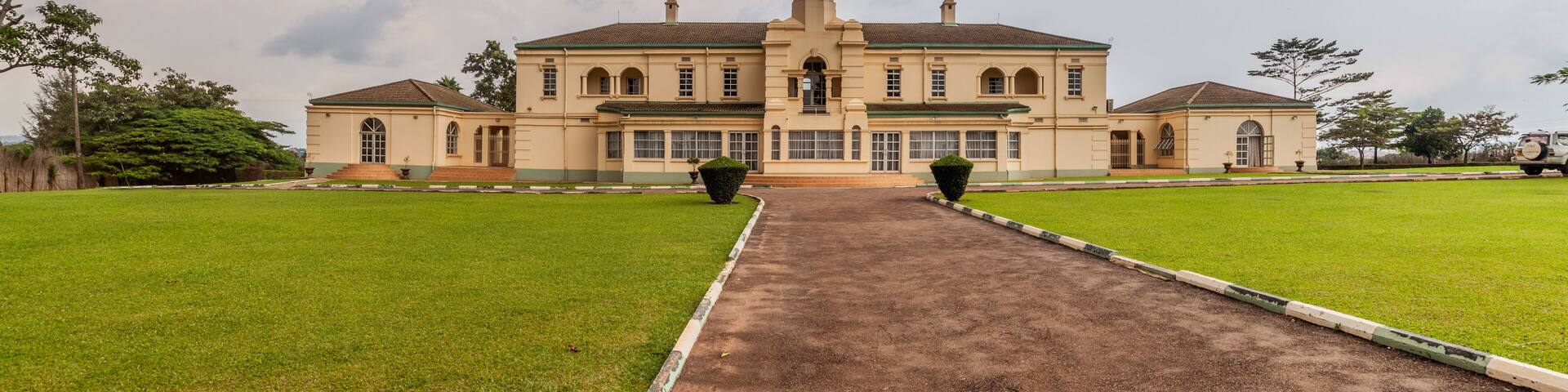 A large, historic building with a central tower and symmetrical wings, surrounded by well-maintained lawns.