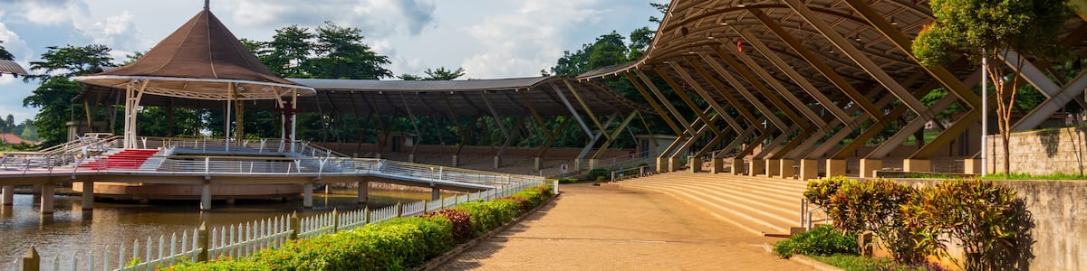 Une promenade au bord de la rivière, agrémentée d’un pavillon couvert, d’une grande structure en forme de dôme et d’un pont enjambant l’eau.