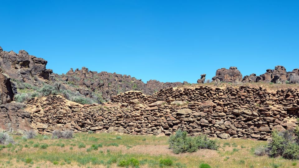 A rocky desert landscape with a prominent rock formation and a large pile of stones.