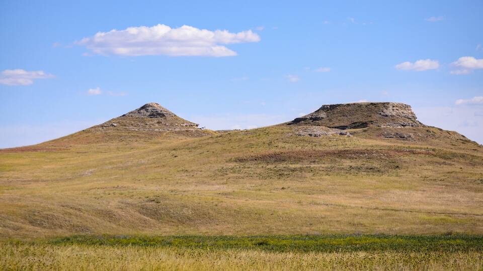 A grassy hill with two prominent mounds.
