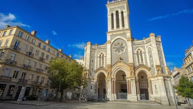 Uma igreja histórica com uma alta torre de sino e entradas em arco.
