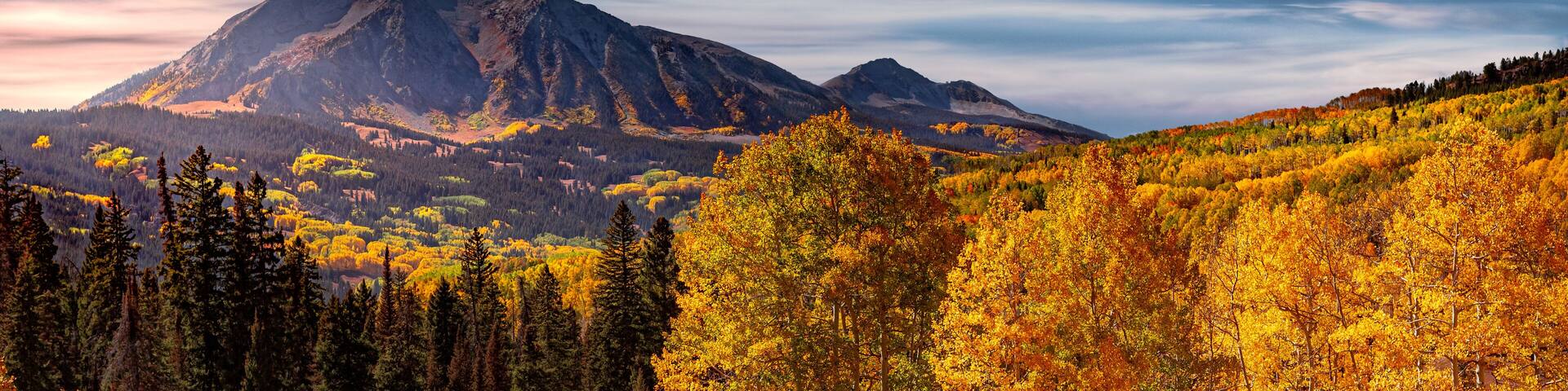 A mountain range with autumn foliage and a clear sky.