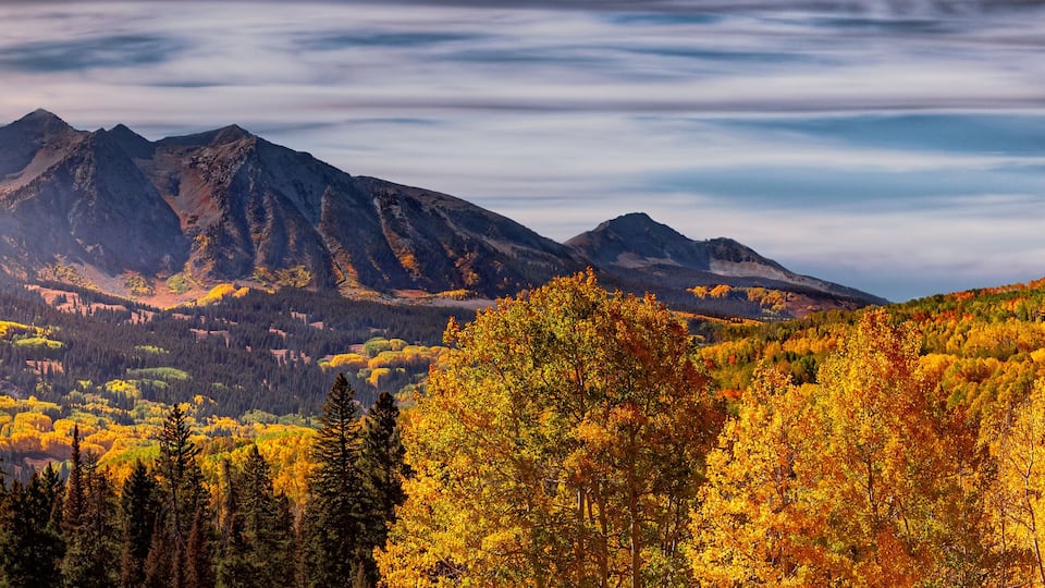 A mountain range with autumn foliage and a clear sky.