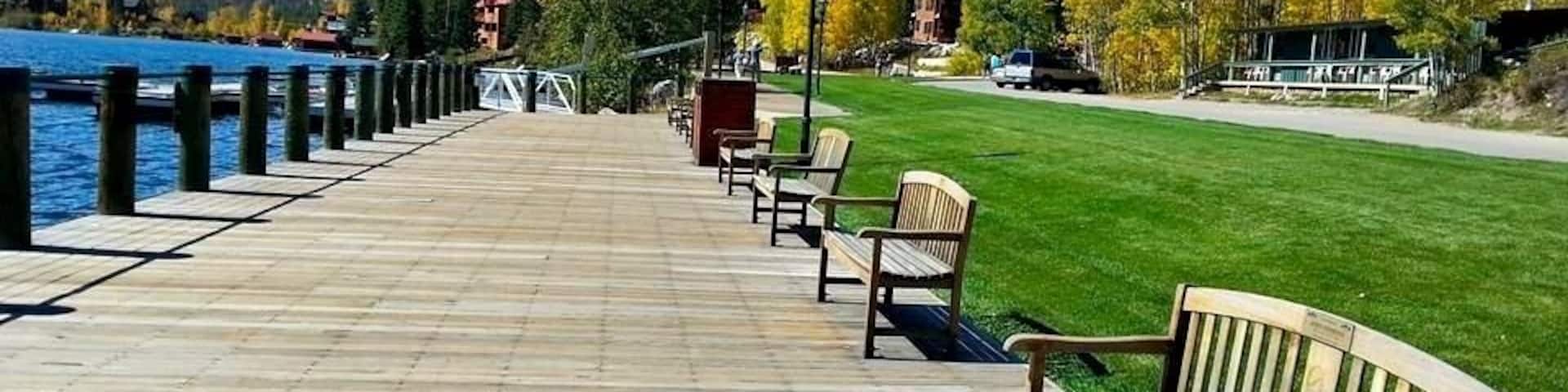 A wooden pier extending into a lake, with benches and a lamp post.