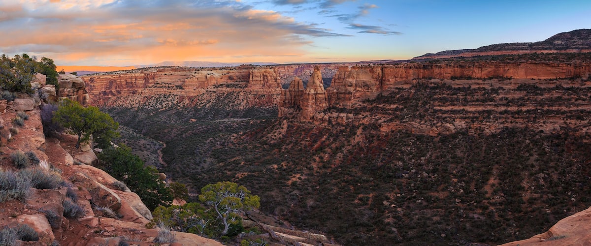 A canyon landscape with layered rock formations and sparse vegetation.