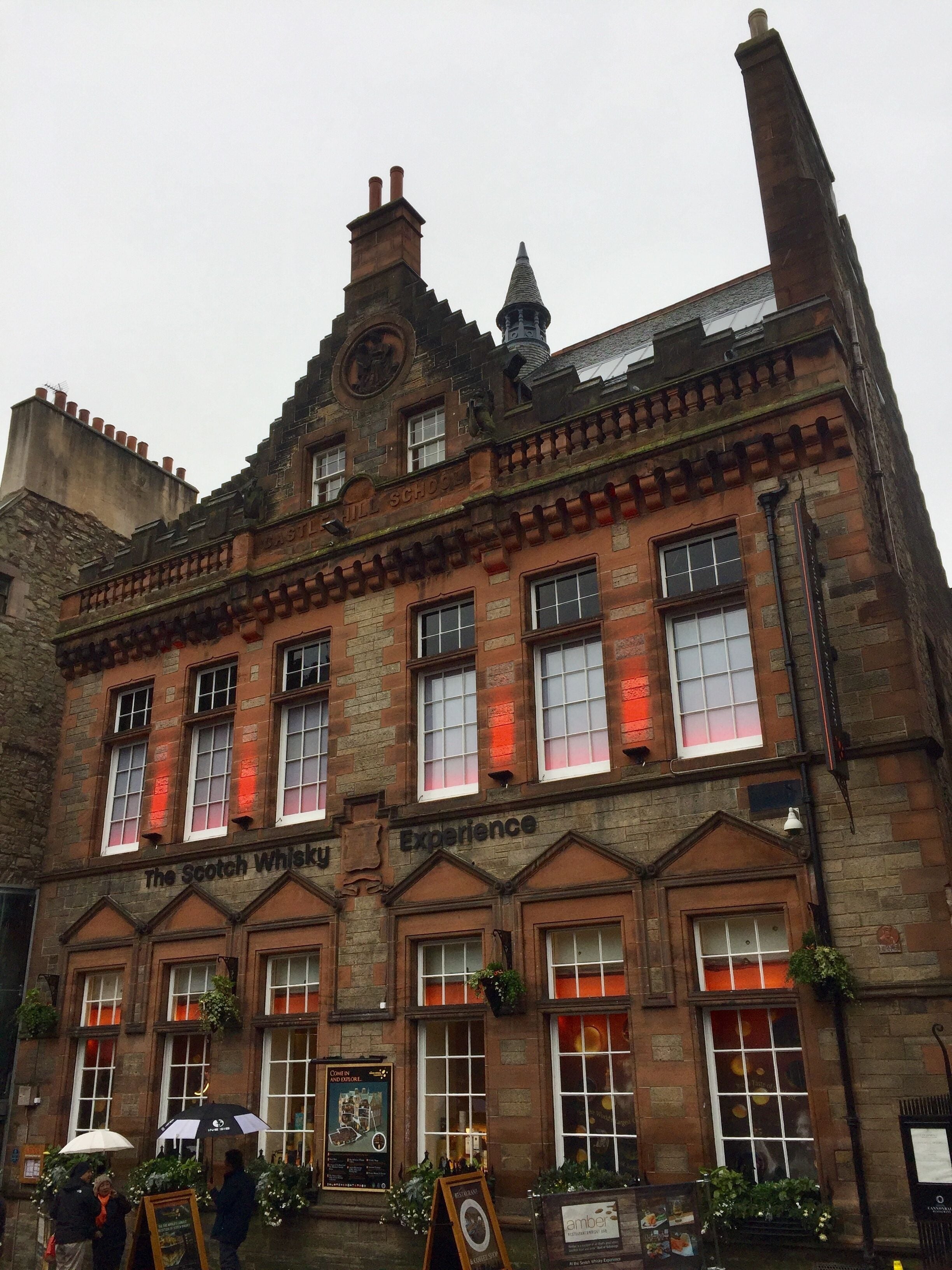 A historic building with the sign "The Scotch Whisky Experience" and a clock on the facade.