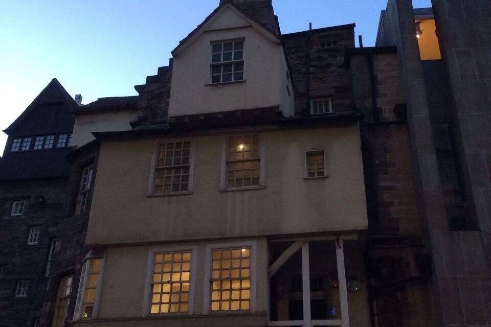 A historic building with a steeply pitched roof, dormer windows, and a stone facade.