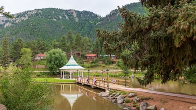 Un lac paisible, avec un pont en bois, un kiosque et des maisons, le tout sur fond de montagnes.