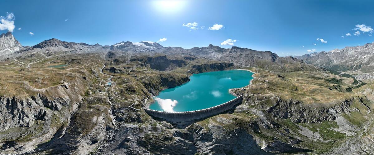 A mountain landscape with a large turquoise lake and a dam.