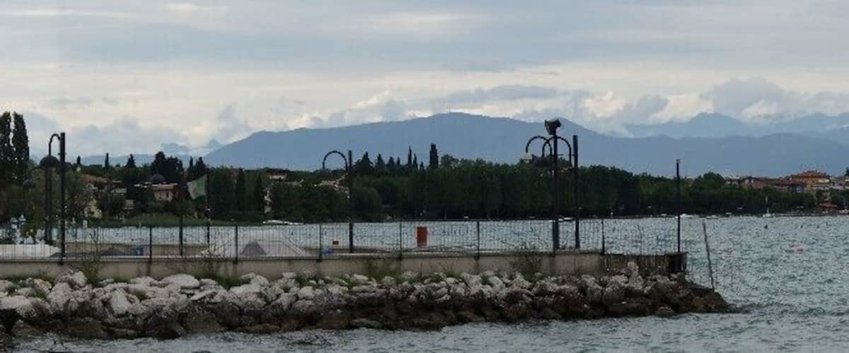 A lake with mountains in the background, a pier, and a flag.
