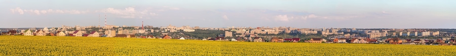 Large wide panorama of the southern residential district of Belgorod city. White city, Russia. Skyline of the city on hills behind a sunflowers field.