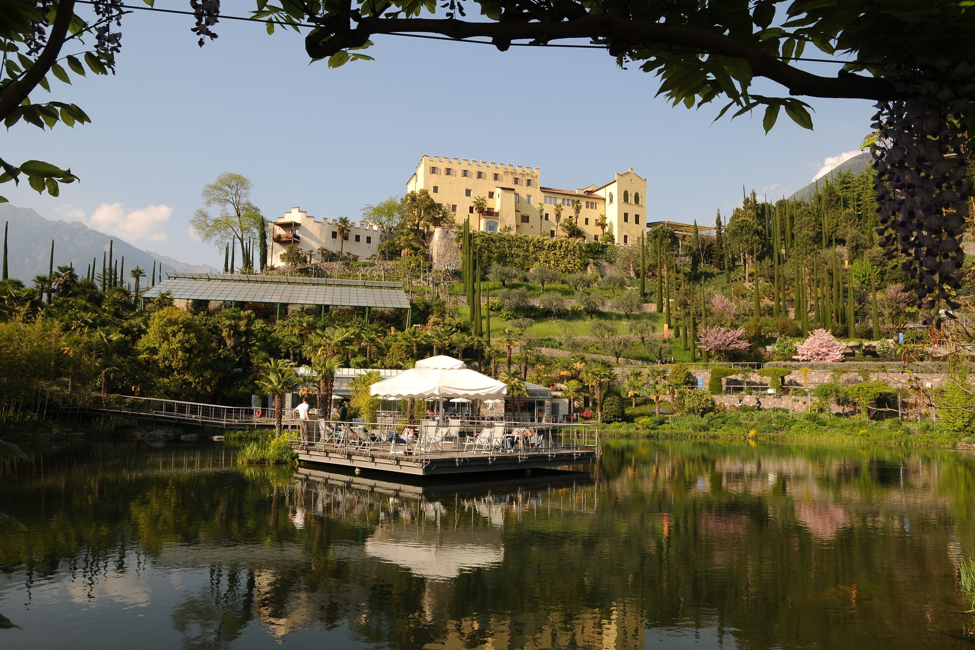 A lake with a boat, a bridge, and a large building on a hill.