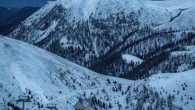 A snow-covered mountain landscape with a small cabin and ski lift.