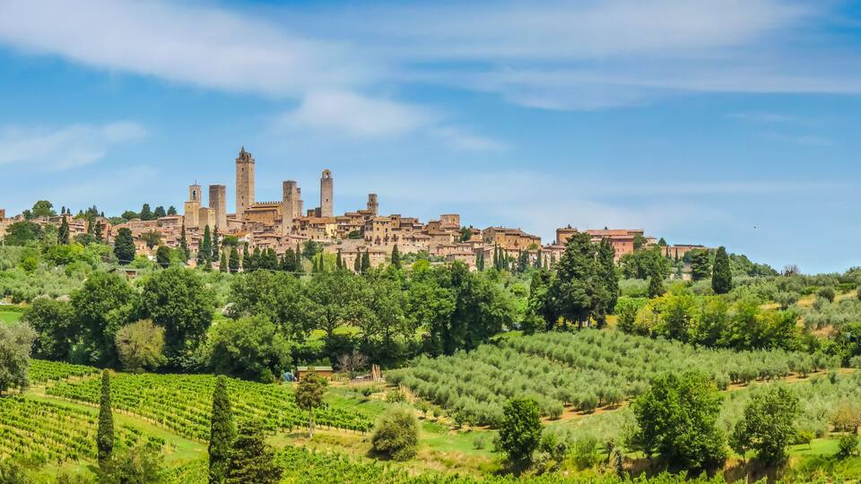 A historic town with medieval architecture, terraced vineyards, and rolling hills.