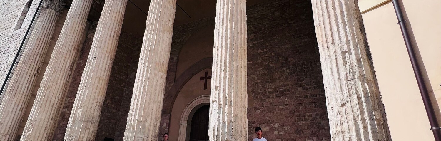 Un edificio histórico con amplias columnas y una torre del reloj.