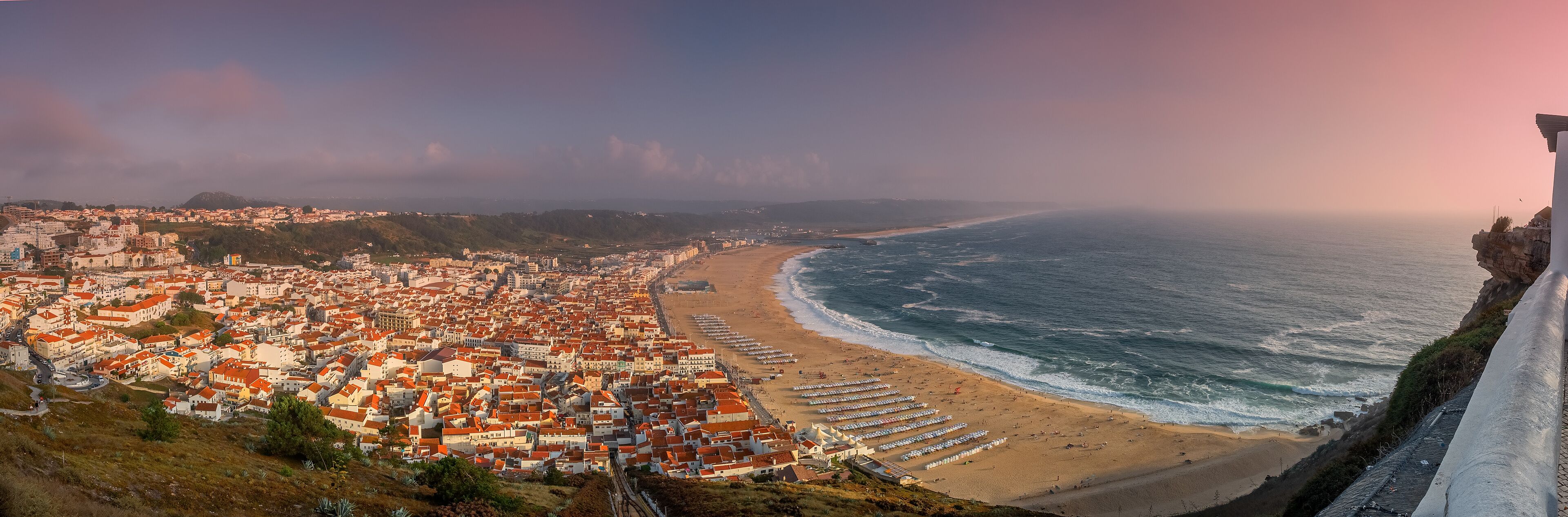 A coastal city with a beach, buildings, and cliffs.