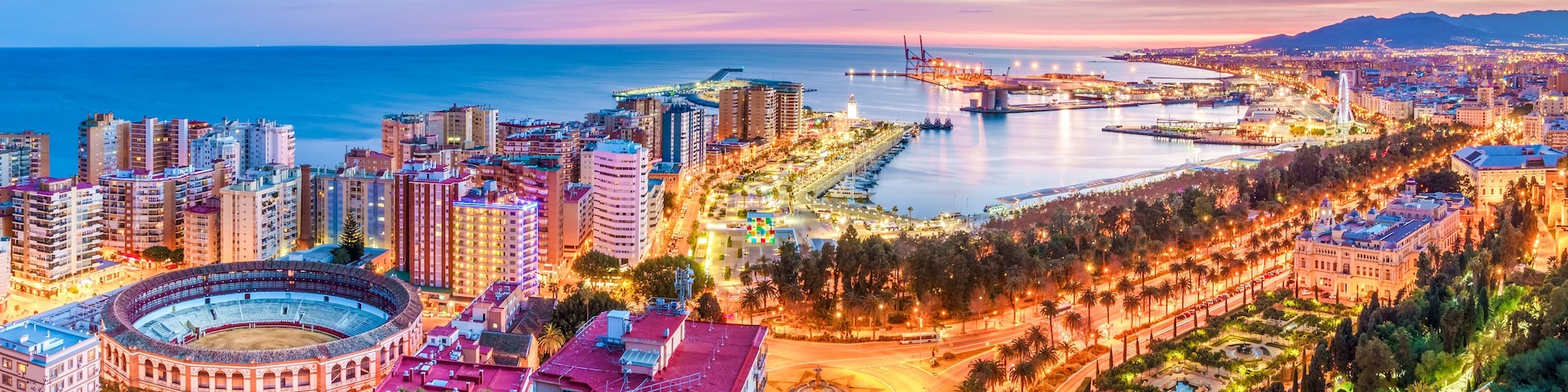 Paisagem costeira urbana com uma arena de touros em destaque, uma ponte e uma combinação de edifícios residenciais e comerciais.