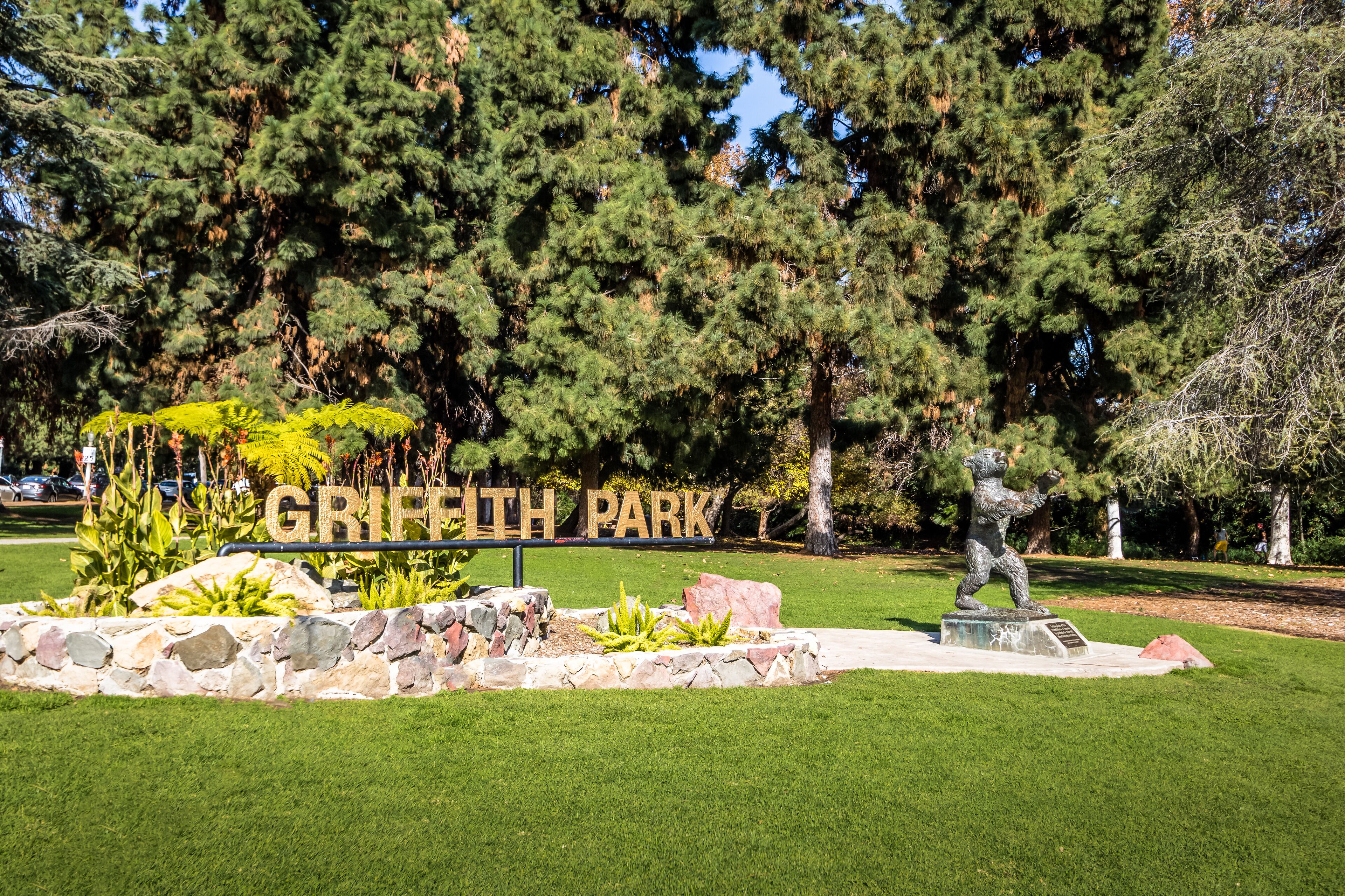 Griffith Park sign, trees, and a statue.