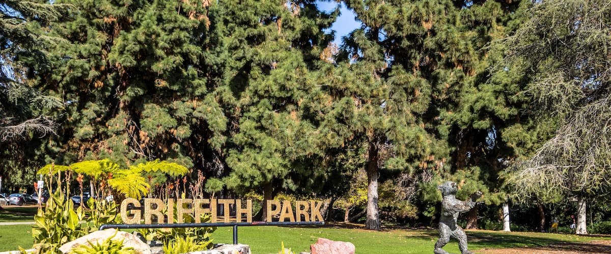 Griffith Park sign, trees, and a statue.
