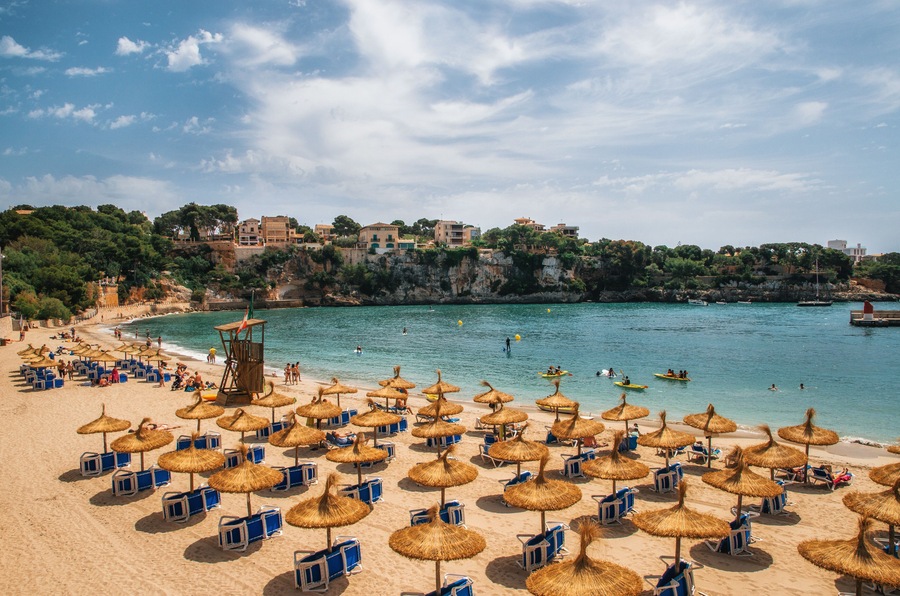 Straw umbrellas on the beach in Porto Cristo on Mallorca, Balearic Islands, Spain; Shutterstock ID 448705021