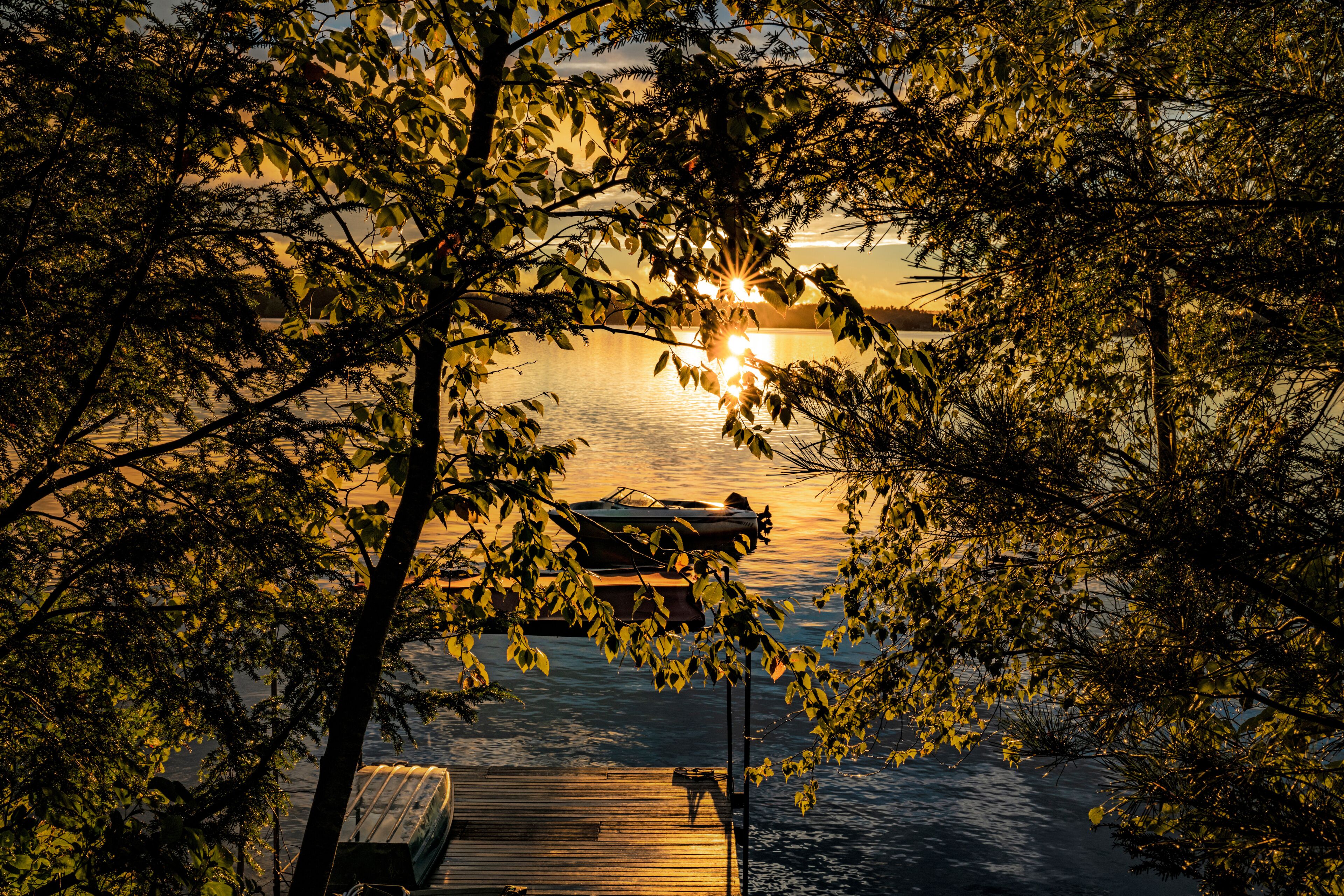 Sunrise on a northern lake with a boat through the trees