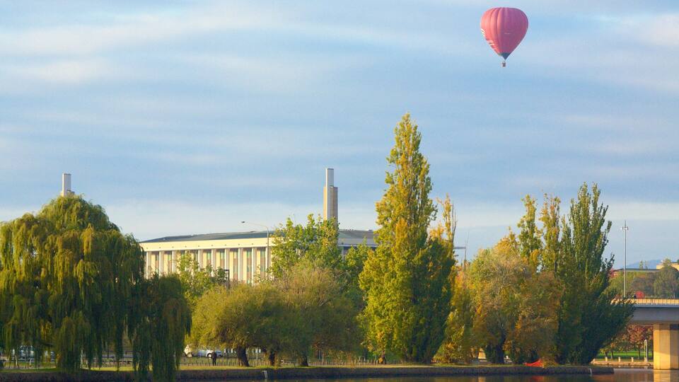 Eine Heißluftballon, Bäume und ein Gebäude mit hohen Schornsteinen.