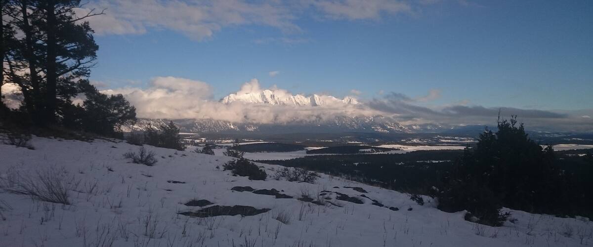 A snowy mountain landscape with a clear sky and distant snow-capped peaks.