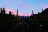 A forested mountain landscape with a sunset sky.