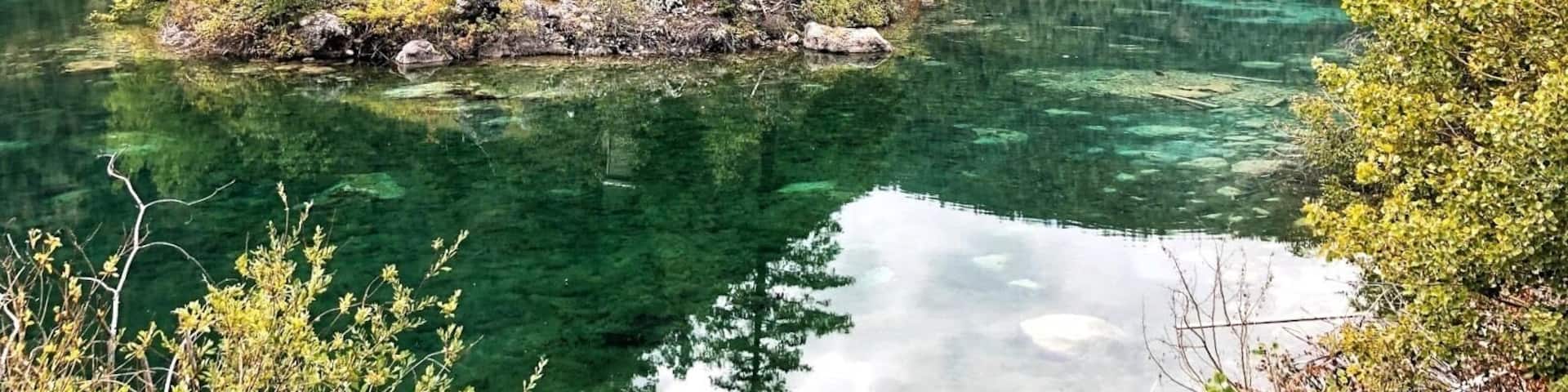 Un lac aux eaux limpides, entouré d’une forêt dense et de montagnes.