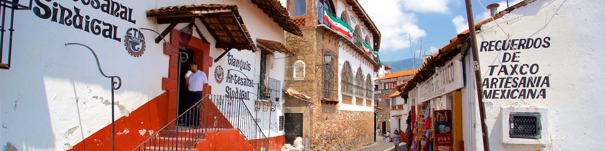 Une étroite rue pavée, bordée d’immeubles ornés de fresques et de panneaux en espagnol, dont un pour « Tianquisi Artesanal Sindical ».