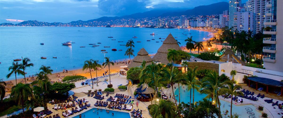 A resort with a pool, palm trees, and a beach with boats.
