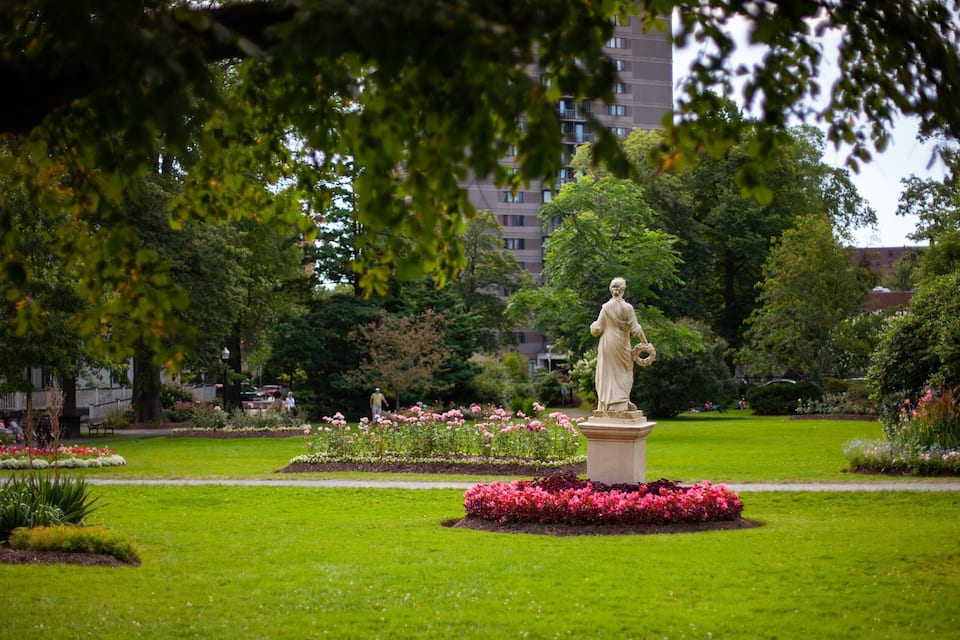 A statue in a park with a building in the background.