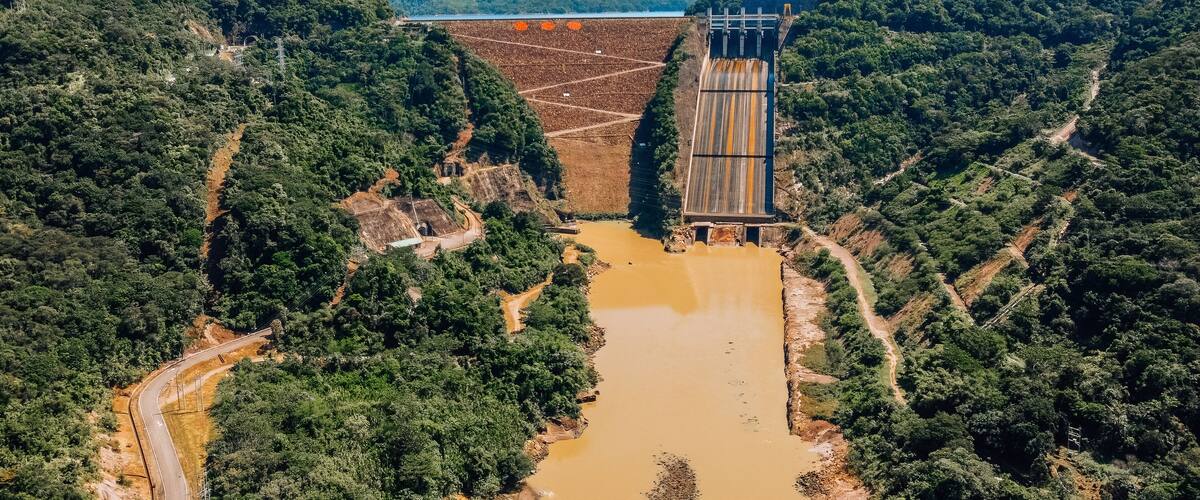 A dam with a river flowing through a forested valley.