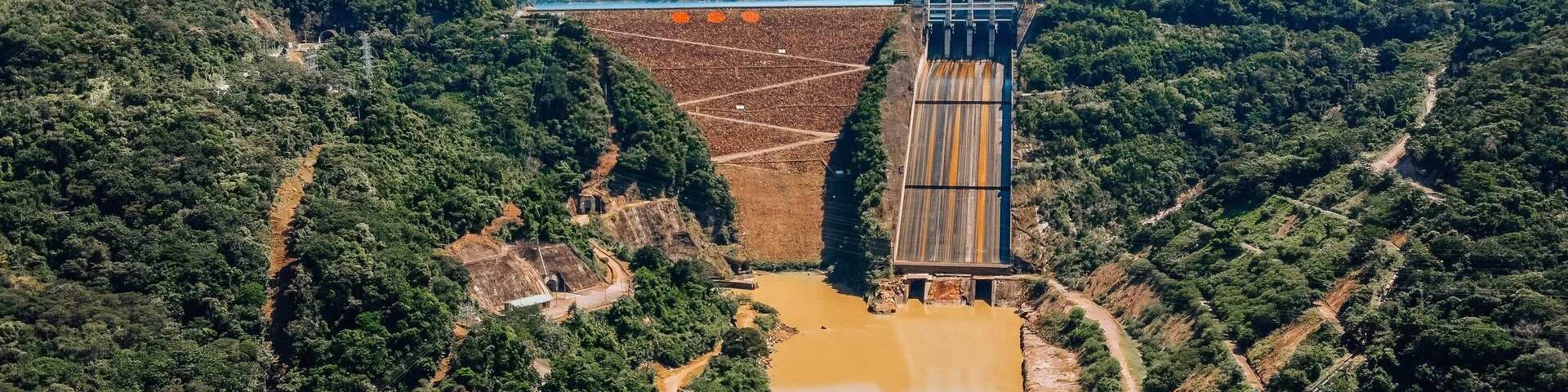 A dam with a river flowing through a forested valley.