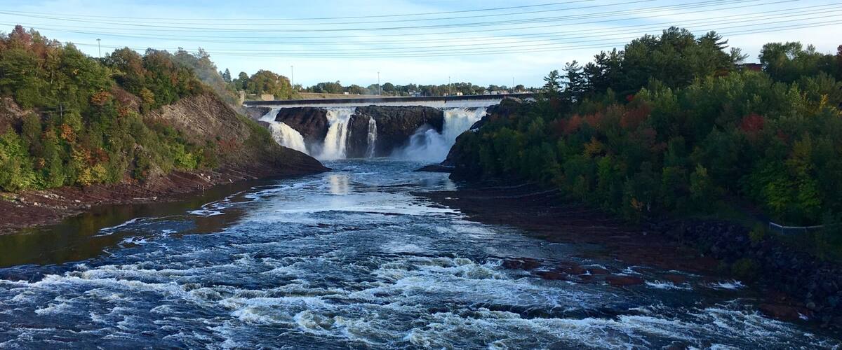 A river with a waterfall and a bridge.