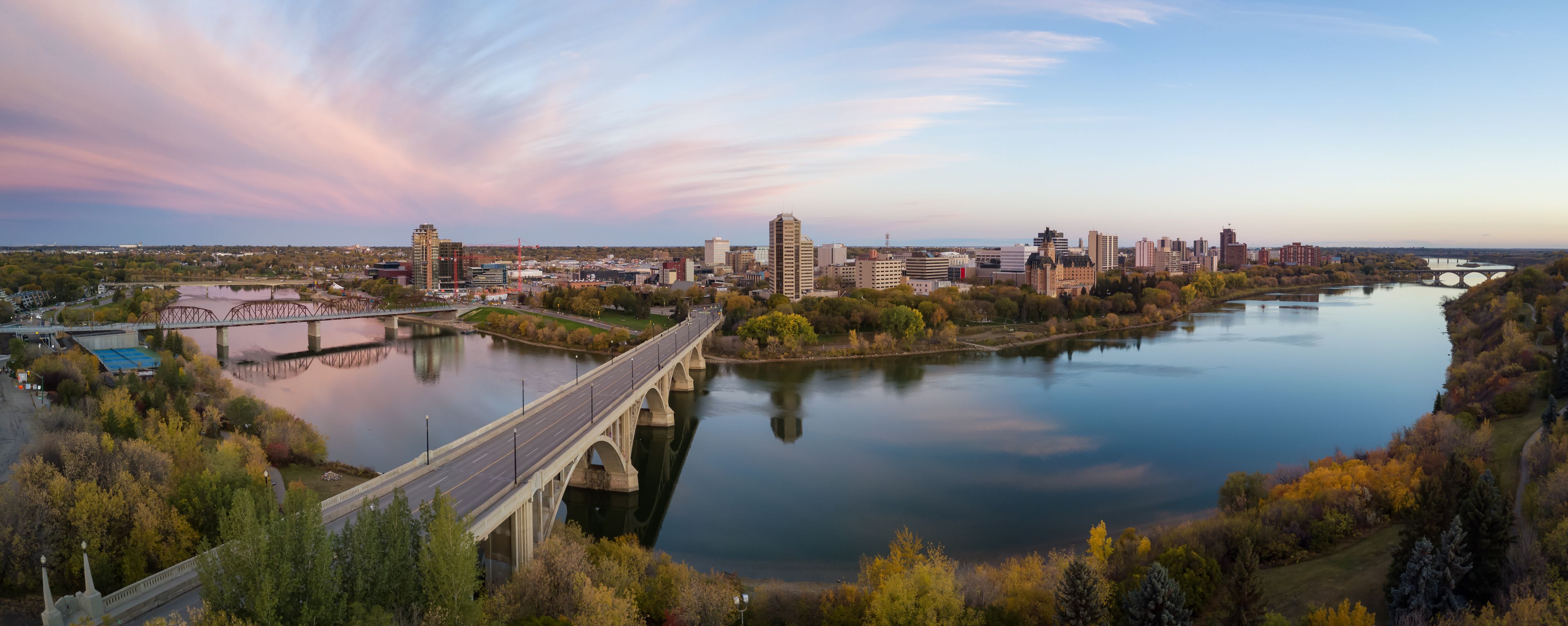 Un río con un puente, el perfil urbano de una ciudad y follaje otoñal.