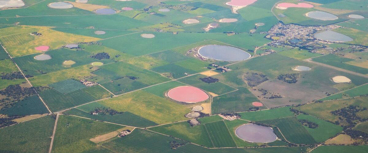 An aerial view of a landscape with numerous circular water bodies and green fields.