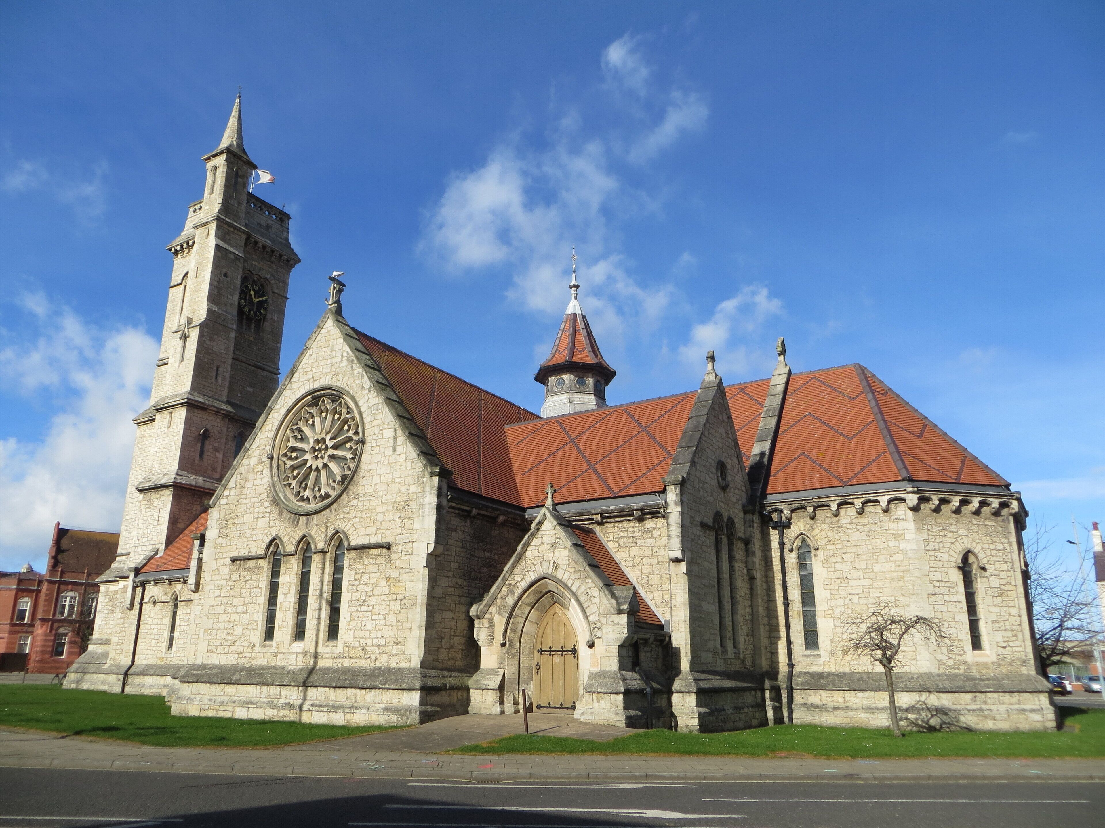 A historic church with a clock tower and a red-tiled roof.