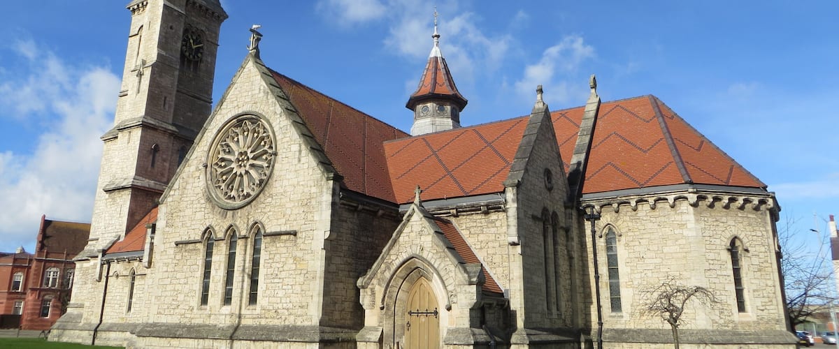 A historic church with a clock tower and a red-tiled roof.