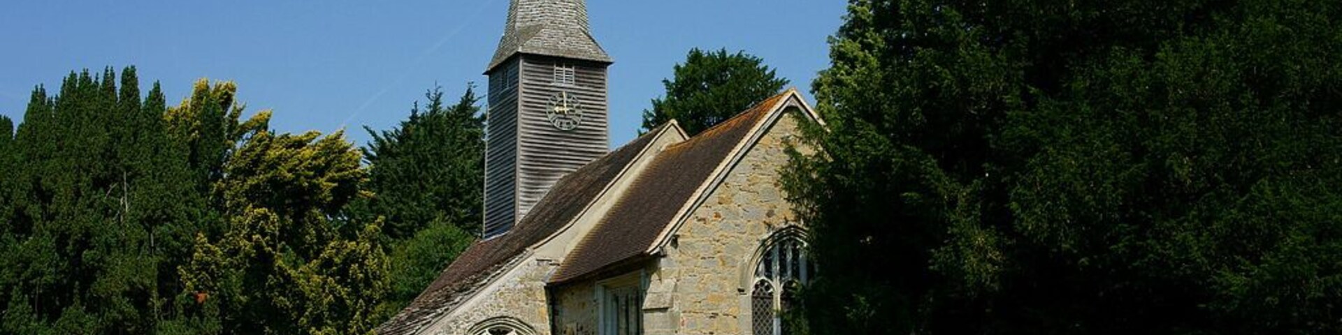 St George's parish church, Crowhurst, Surrey, seen from the southeast. To the right of the church is the Crowhurst Yew, an ancient tree thought to be up to 4000 years old. Despite the trunk being hollow, the tree seems to be in good health.