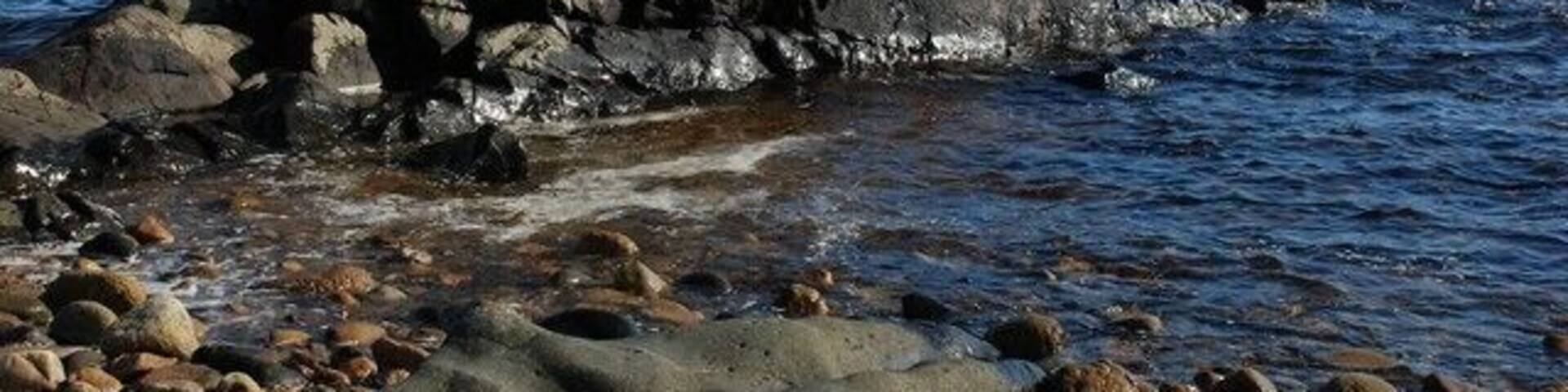A rocky shoreline with a prominent rock formation and calm sea.