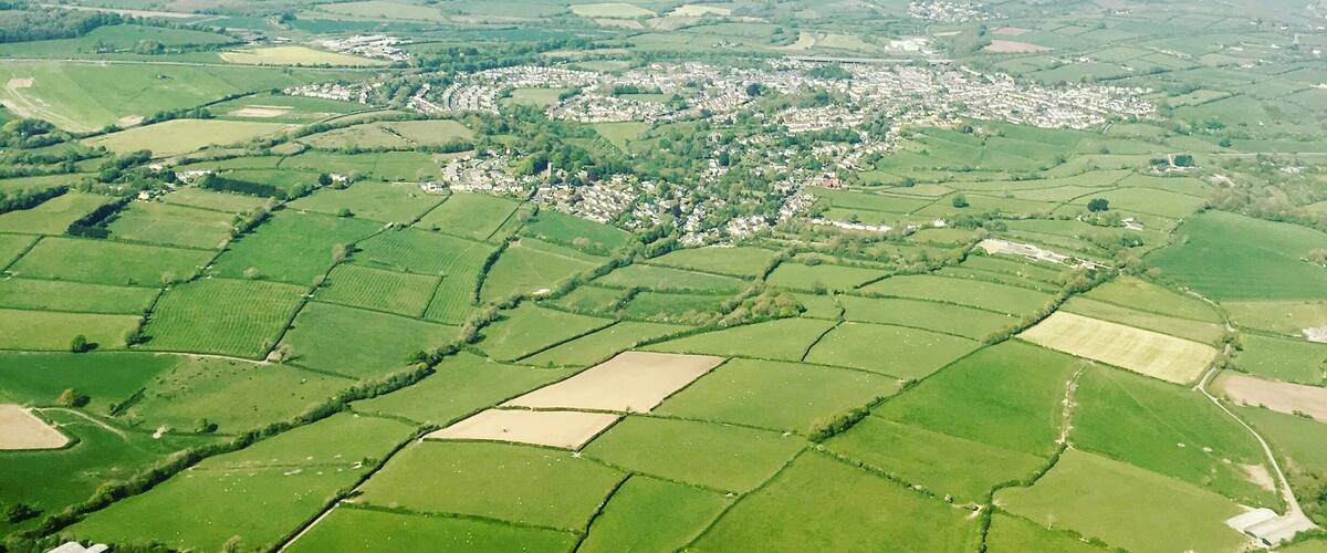 A rural landscape with fields, a small village, and rolling hills.